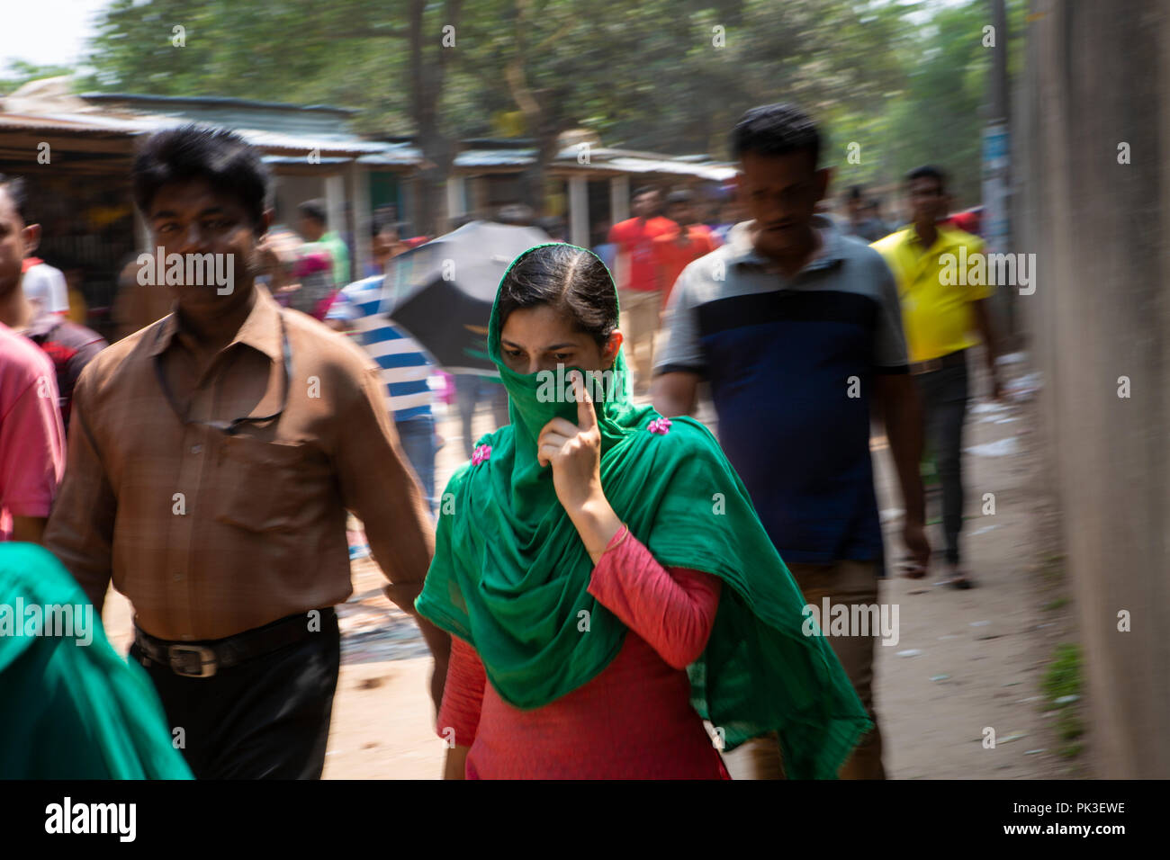 Une femme à l'aide de son sari pour protéger sa bouche de la pollution de l'air sur sa façon de travailler. Banque D'Images