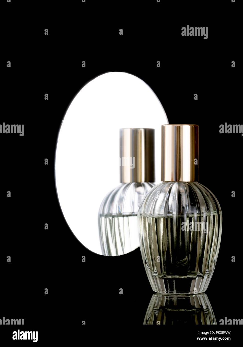Un élégant flacon de parfum en verre clair sur un fond noir brillant avec réflexion aussi en miroir derrière. Avec copyspace. Banque D'Images
