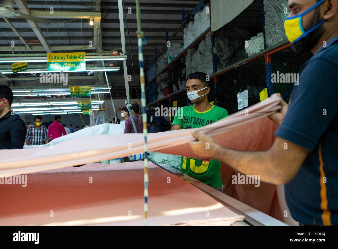 Les travailleurs du vêtement et de mesure des longueurs de coupe de matériaux à l'intérieur d'une usine de confection au Bangladesh. Banque D'Images