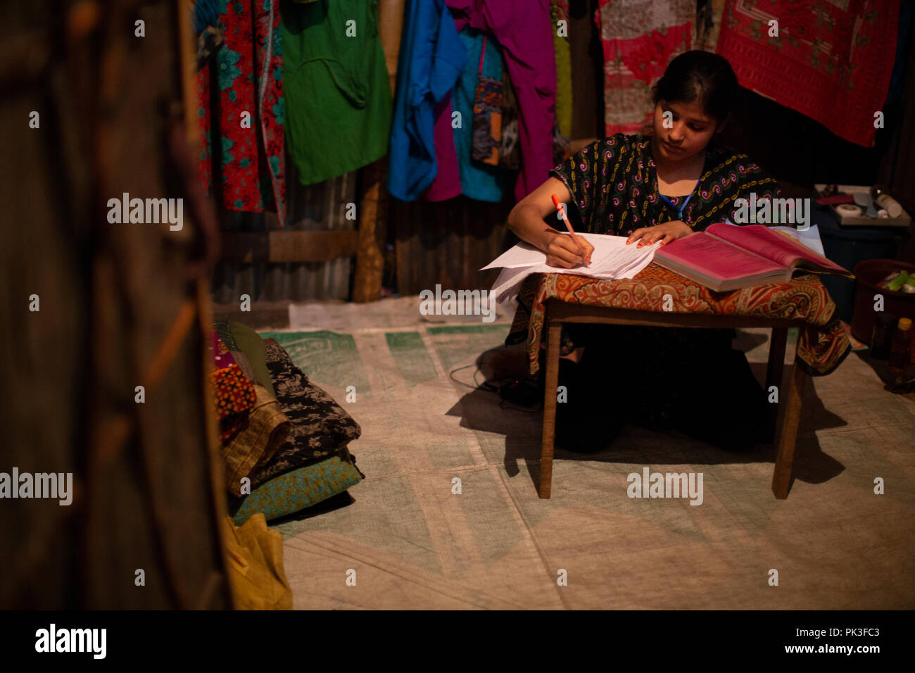 Une travailleuse du vêtement qui étudient pour devenir une infirmière à son domicile dans un taudis de Dhaka, Bangladesh. Banque D'Images