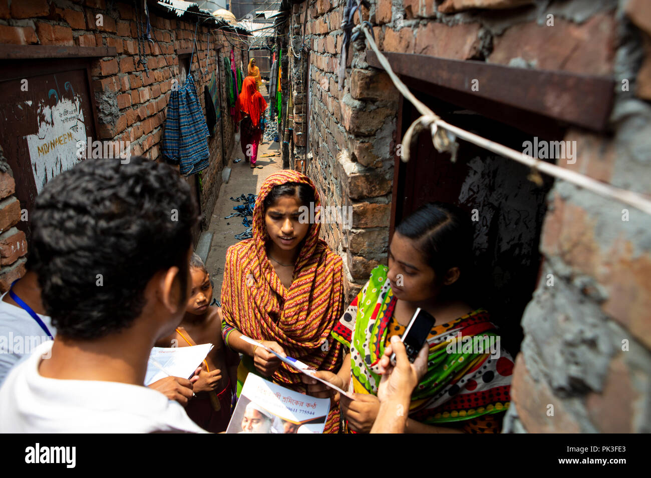 Le personnel de la communauté de parler aux travailleurs du vêtement dans les bidonvilles où ils vivent à Dhaka, au Bangladesh. Banque D'Images