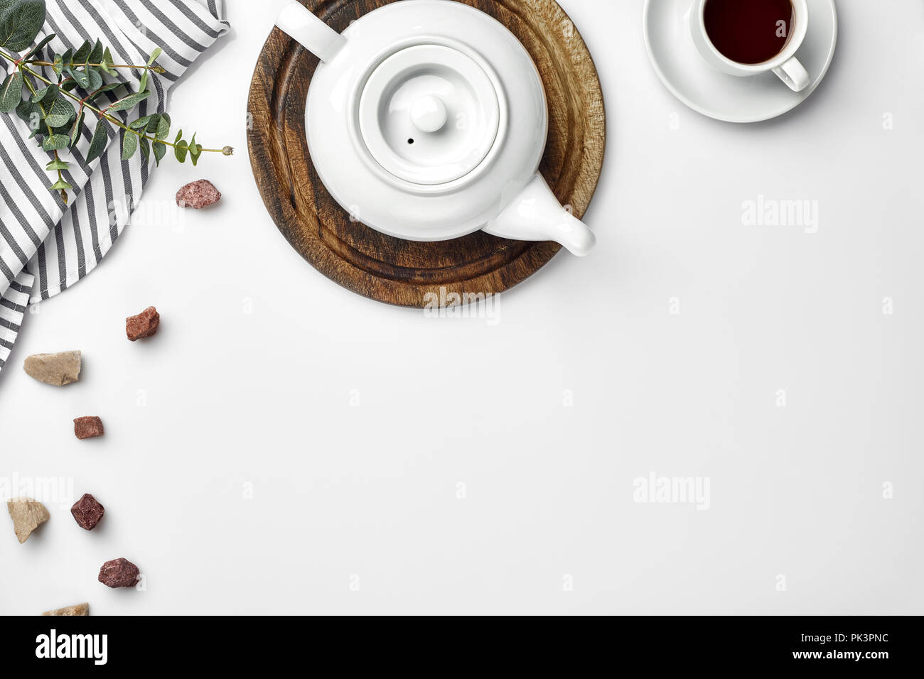 Une théière en porcelaine blanche sur une planche en bois et une tasse blanche avec plateau sur une table. Vue d'en haut. Copier l'espace. Banque D'Images