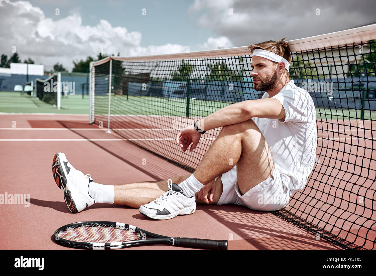 Se détendre après une bonne partie. Cheerful man au repos assis sur le net tennis tennis Banque D'Images