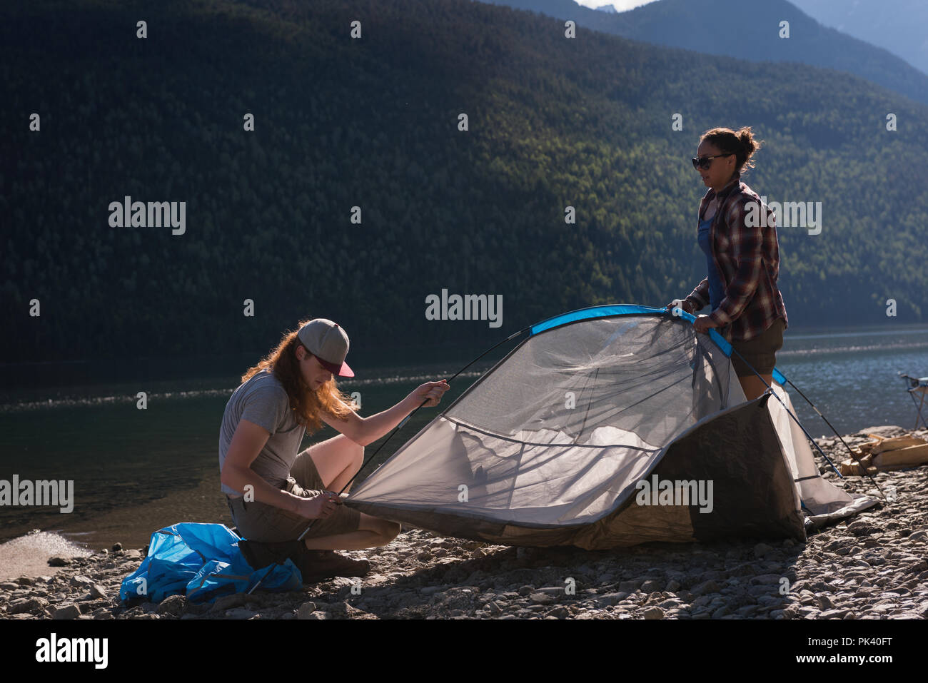 Couple setting up tent près de Riverside Banque D'Images