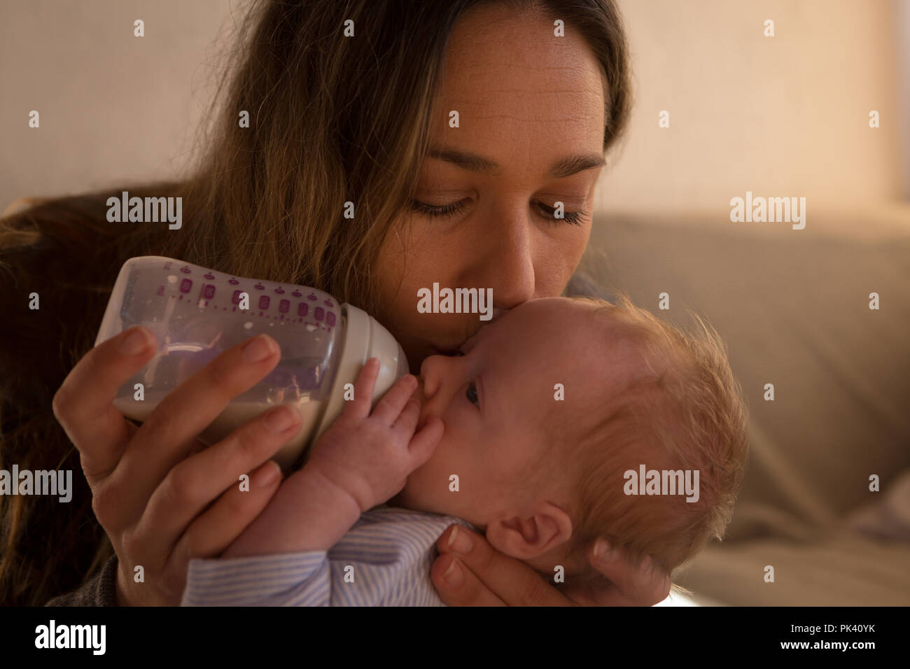 Mère embrassant son bébé lorsqu'il mange à la maison du lait Banque D'Images