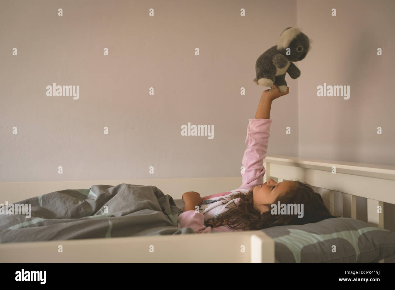 Girl Playing with teddy bear on bed Banque D'Images