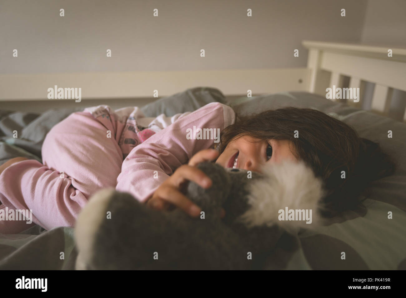 Girl Playing with teddy bear on bed Banque D'Images