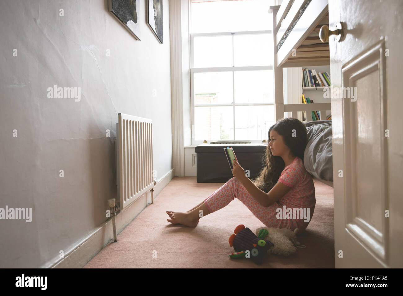 Girl reading book in bedroom Banque D'Images