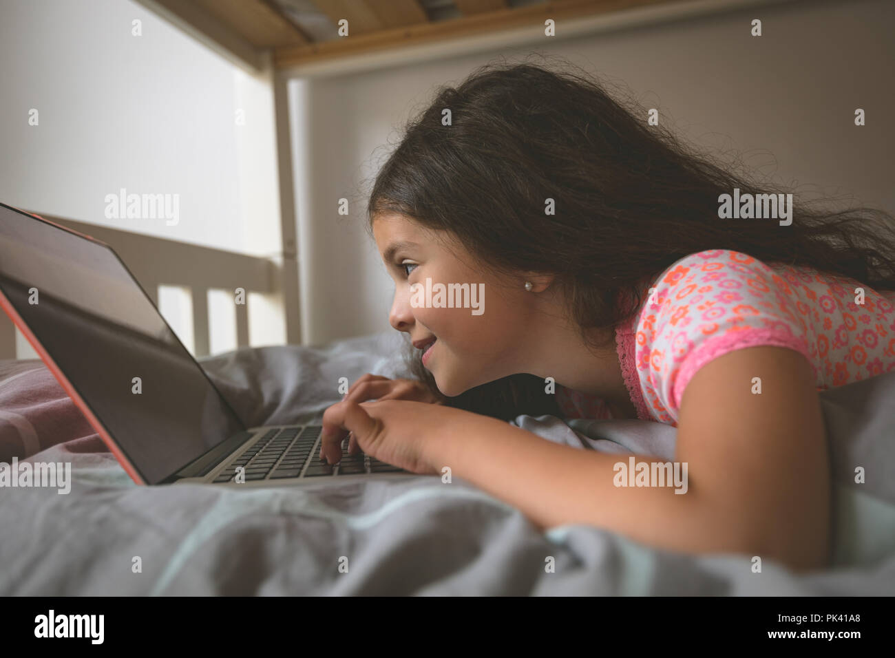 Girl using laptop on lit dans la chambre à la maison Banque D'Images