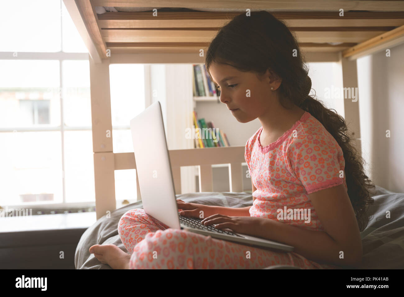 Girl using laptop on lit dans la chambre à la maison Banque D'Images