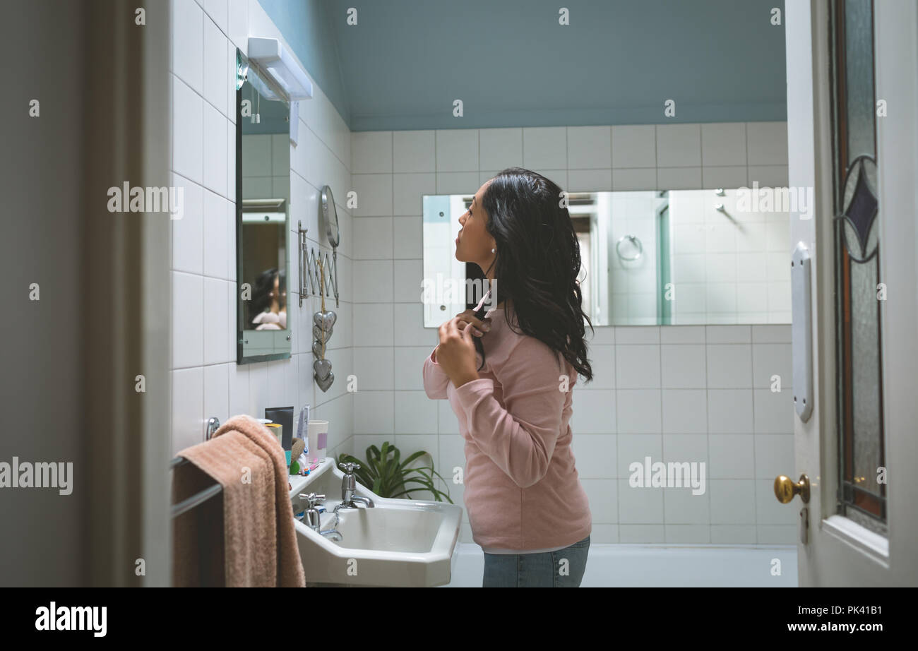 Femme peigner les cheveux avant de mirror miroir de salle de bains Banque D'Images