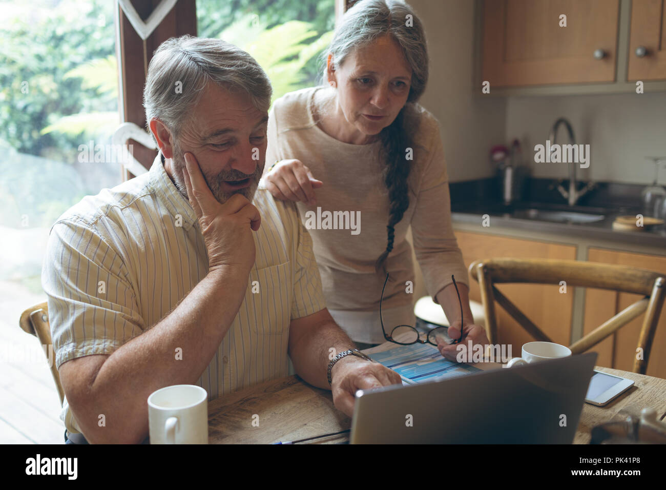Senior couple using laptop on dining table Banque D'Images