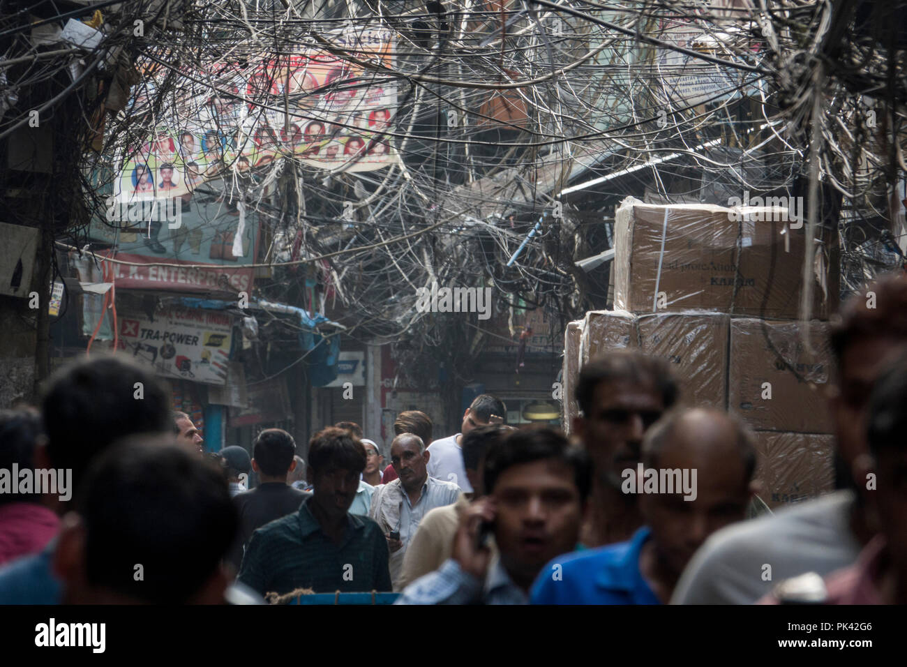 Les piétons circulant dans la rue étroite avec grand nid d'emmêler les câbles d'alimentation de surcharge dans Old Delhi, New Delhi, Delhi, Inde Banque D'Images