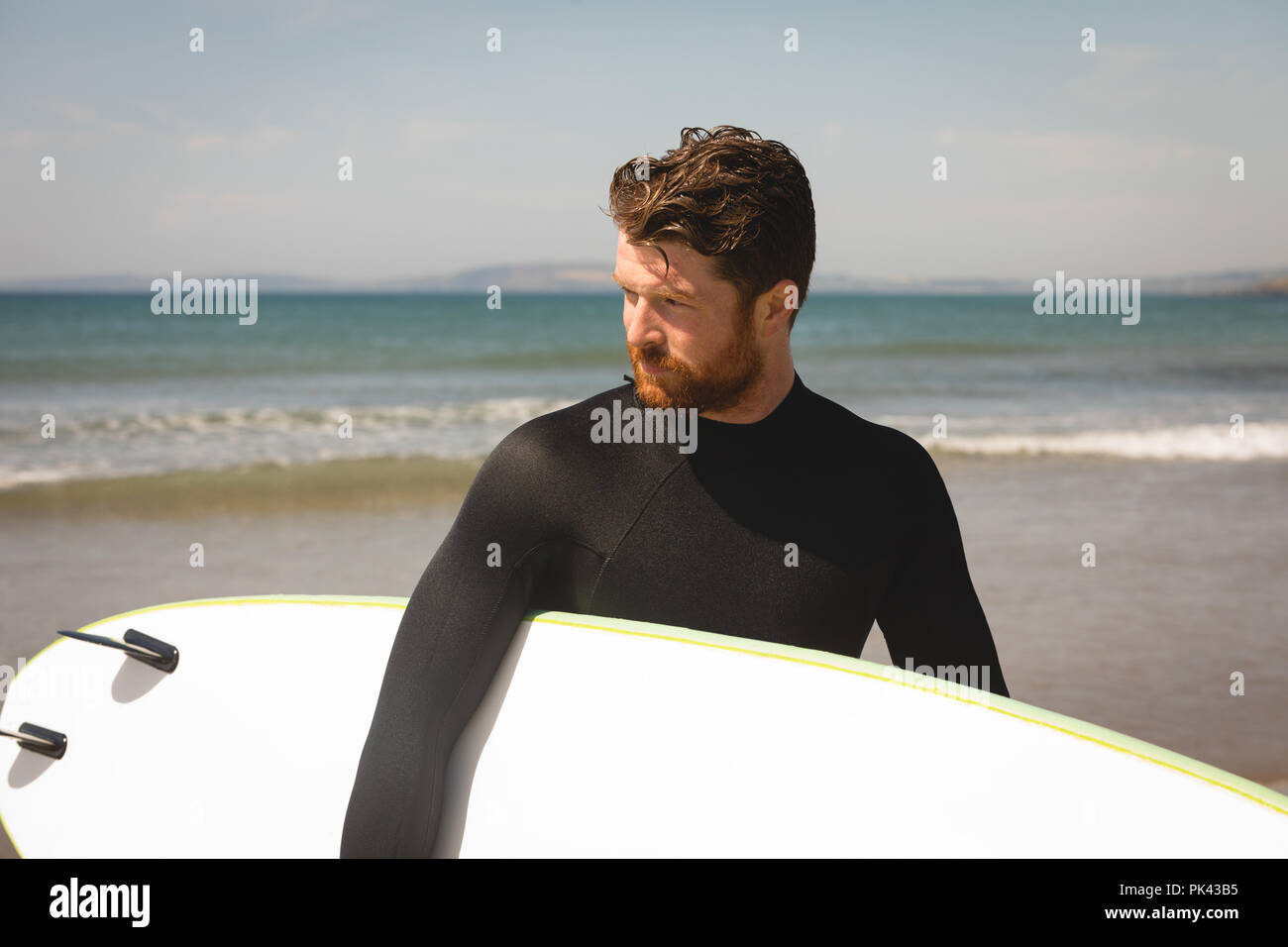 Surfer avec une planche de surf à la plage à pied Banque D'Images