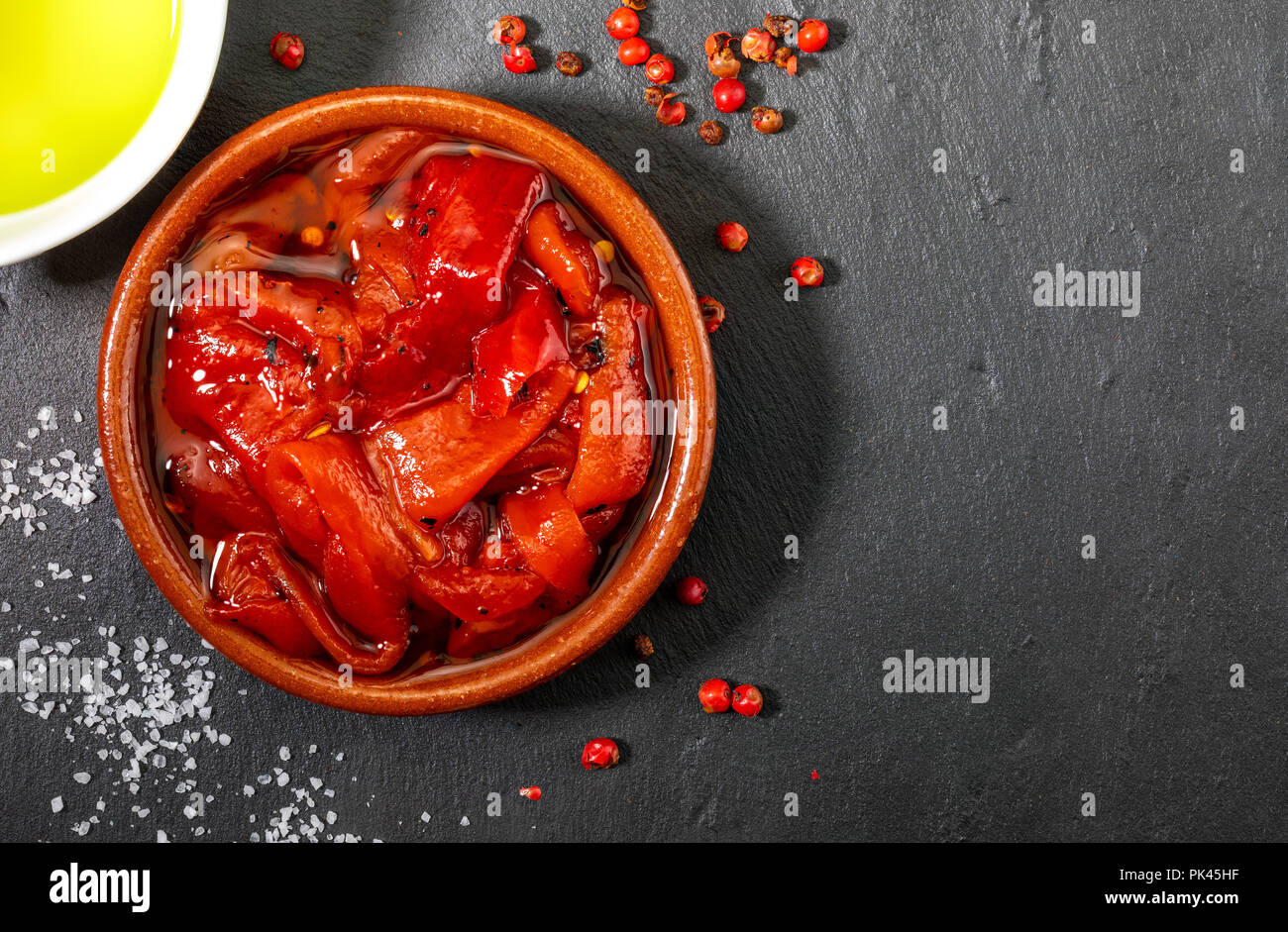 Délicieux et appétissants de poivron rouge rôti à la maison. Huile d'olive vierge extra, sel et poivre. Sur fond texturé en noir. Banque D'Images