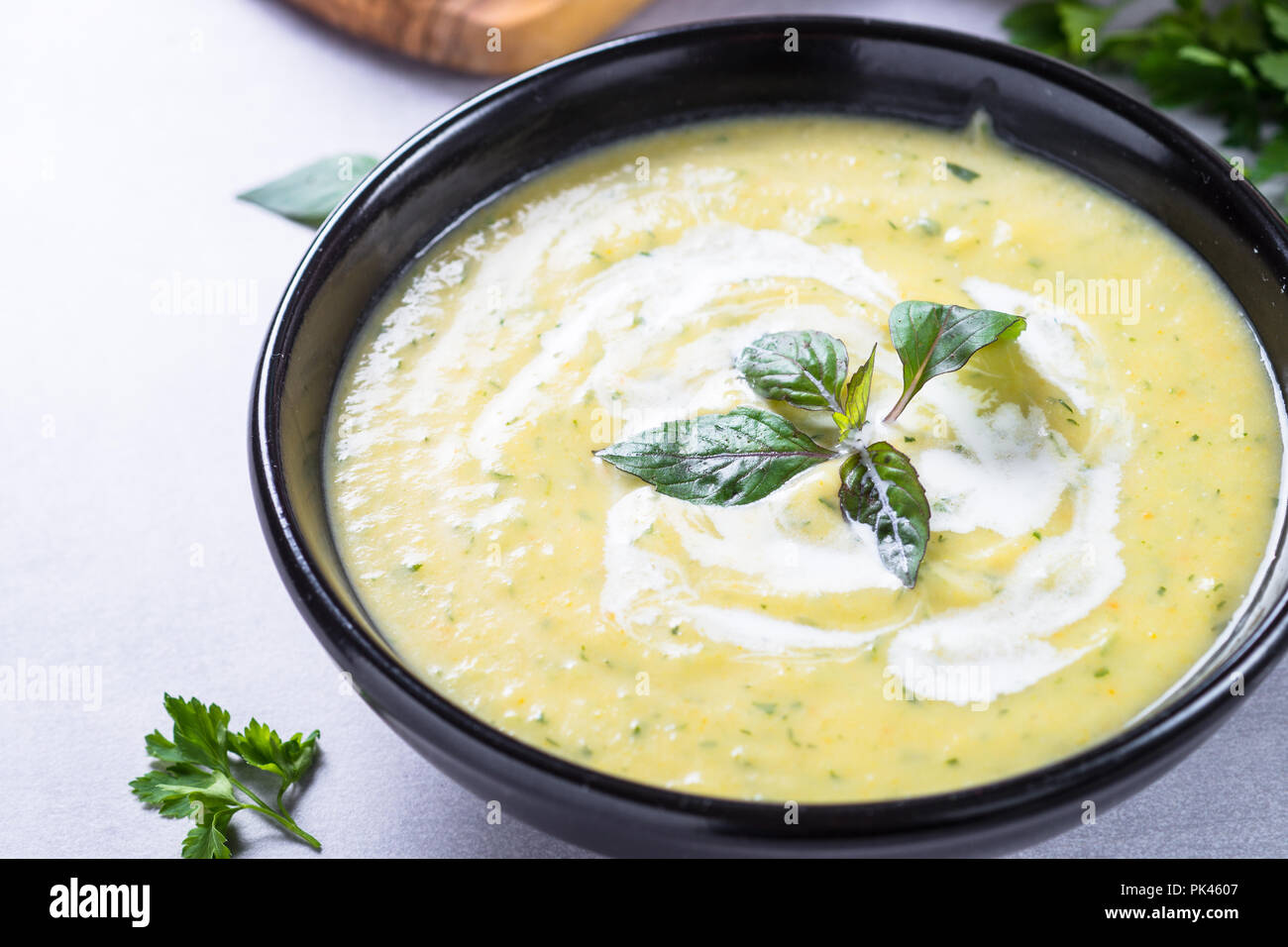 Soupe crème de courgettes purée dans un bol noir. Plat végétarien. Banque D'Images