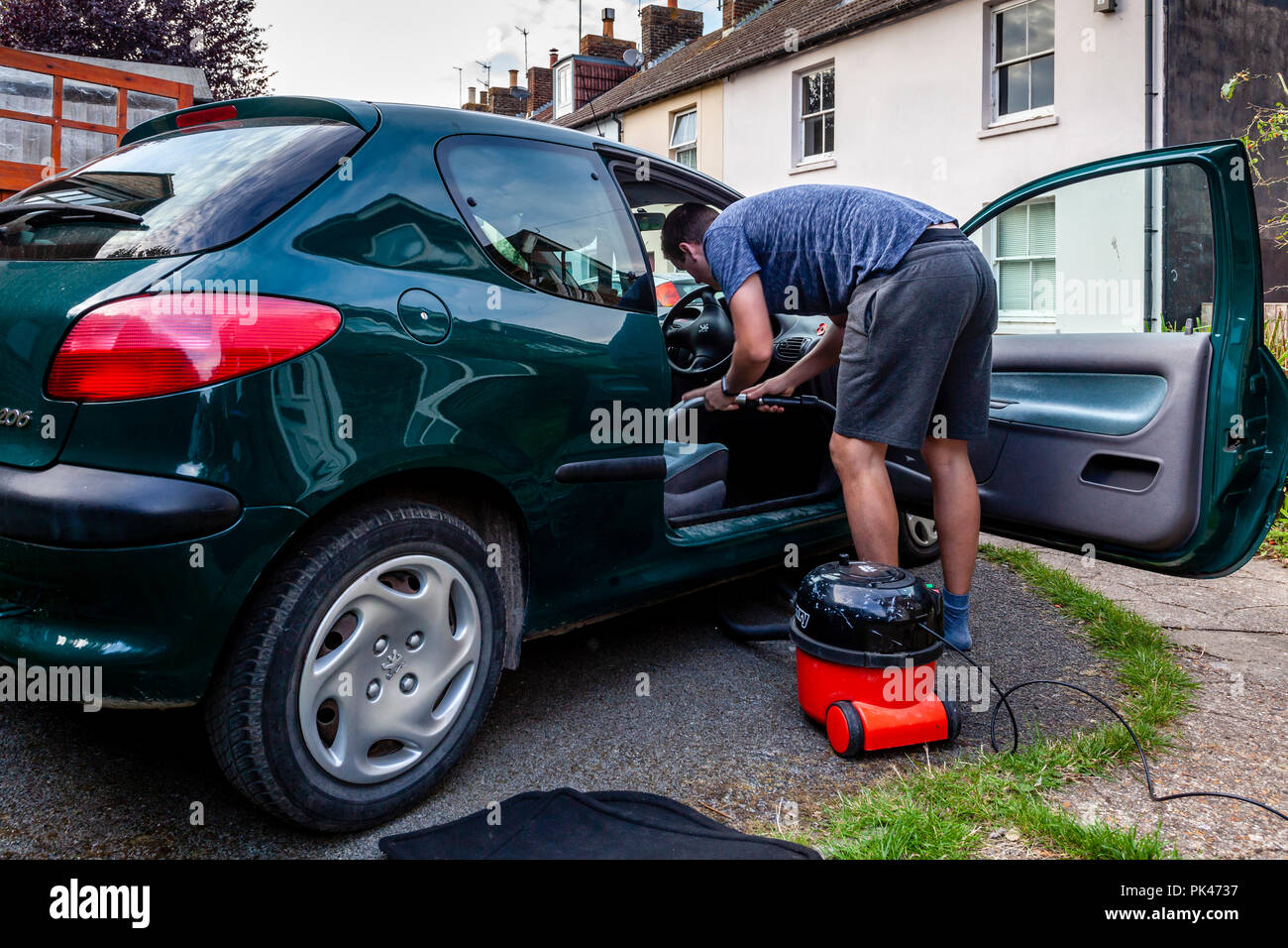 Un jeune homme nettoie sa voiture vide, Sussex, UK Banque D'Images