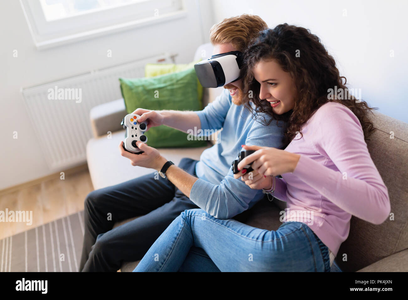 Jeune couple sympathique à jouer à des jeux vidéo avec les casques de réalité virtuelle Banque D'Images