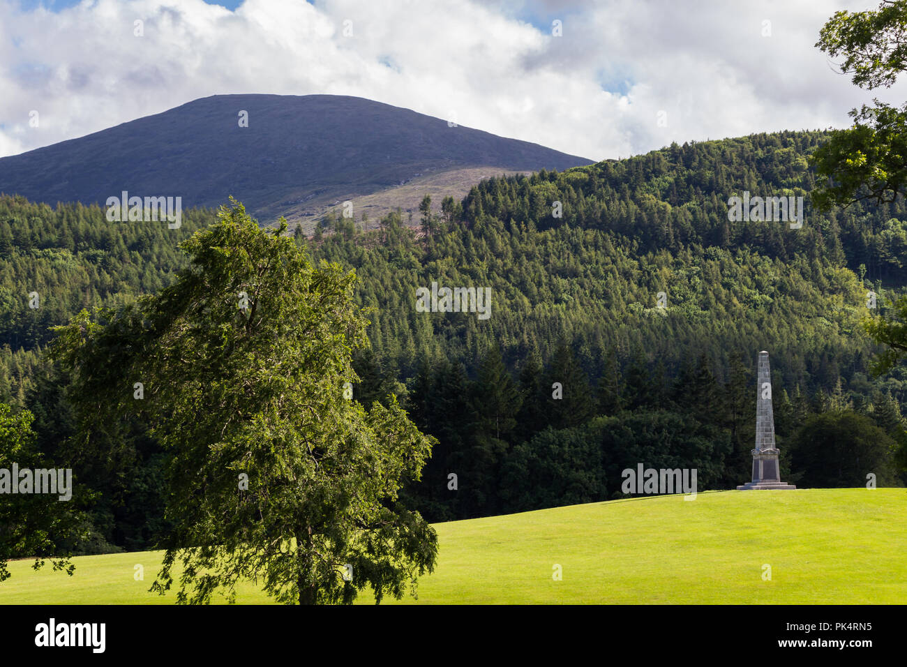 Obélisque commémoratif sur une colline avec des montagnes de Mourne et derrière la forêt dans la distance. Tollymore Forest Park, Newcastle, N.Ireland. Banque D'Images