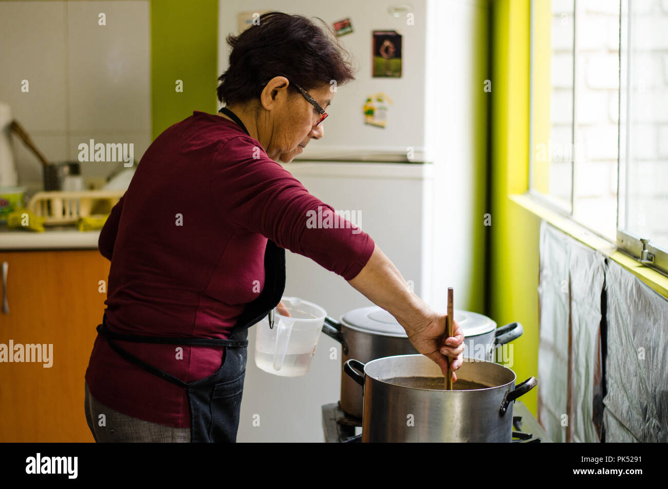 Senior woman la préparation des aliments sains accueil à partir de légumes frais dans la cuisine. Banque D'Images