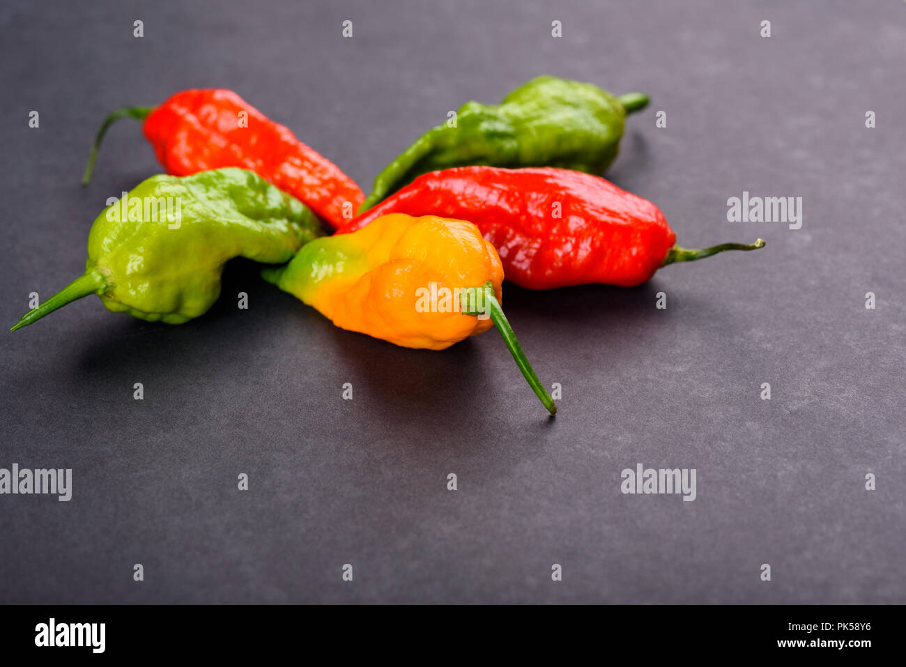 Rouge vert et jaune ghost poivrons sur une surface sombre Banque D'Images