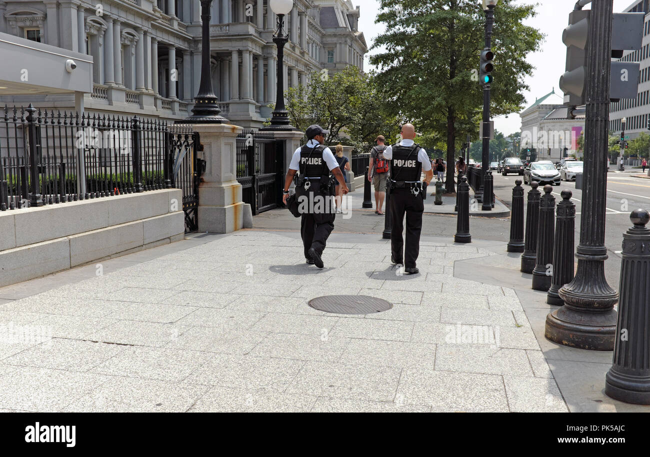 Deux policiers patrouillent le trottoir à l'extérieur de l'Eisenhower Executive Office Building à Washington DC. Banque D'Images