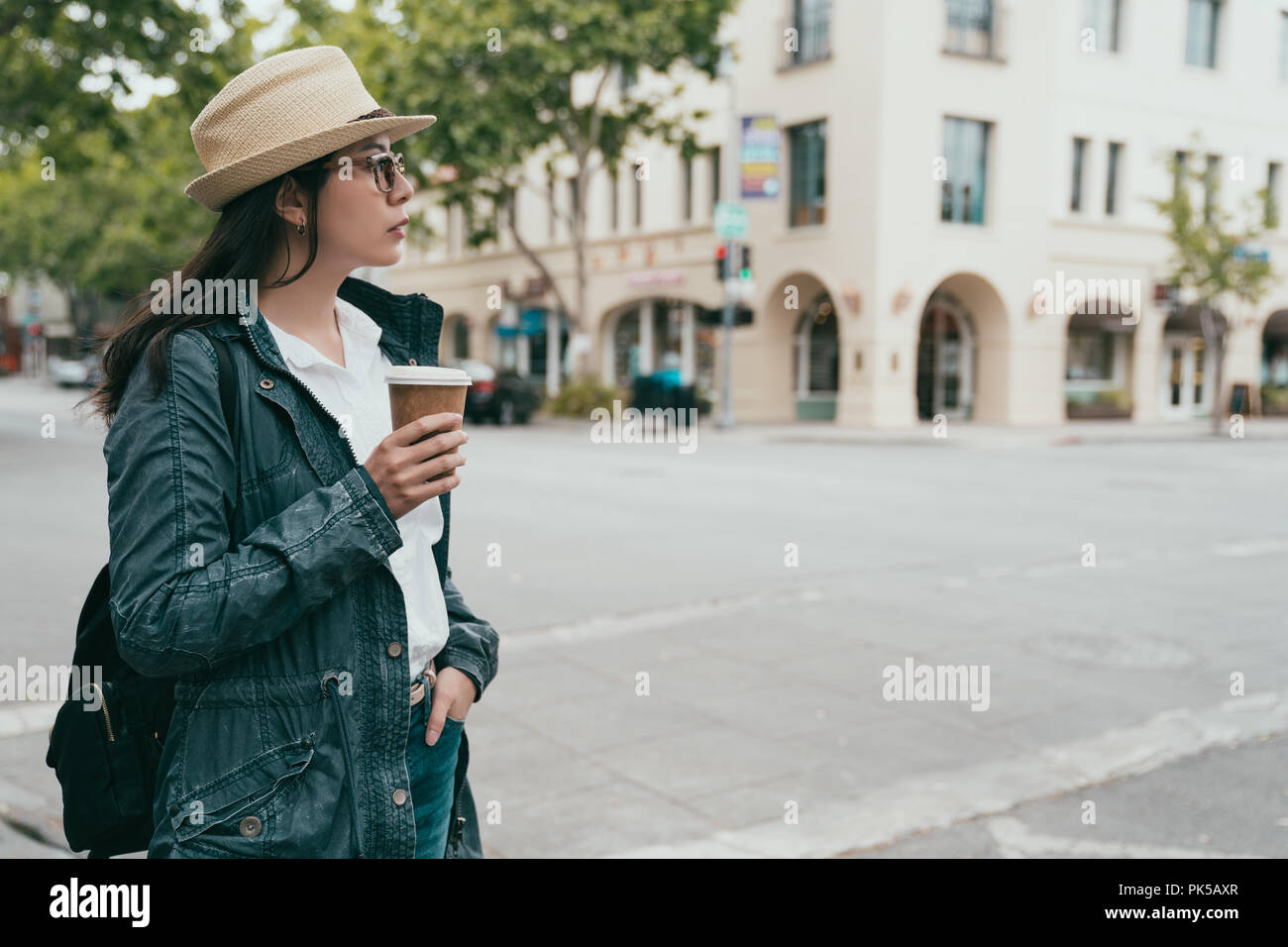 Belle femme élégante tenant son café et debout dans la rue en attente. Banque D'Images