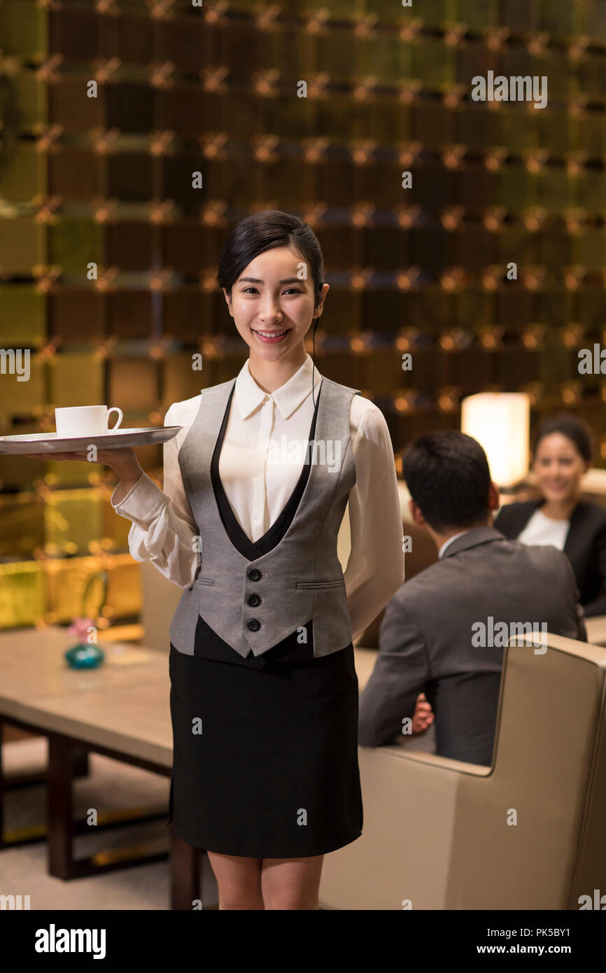 Cheerful young waitress serving coffee Banque D'Images