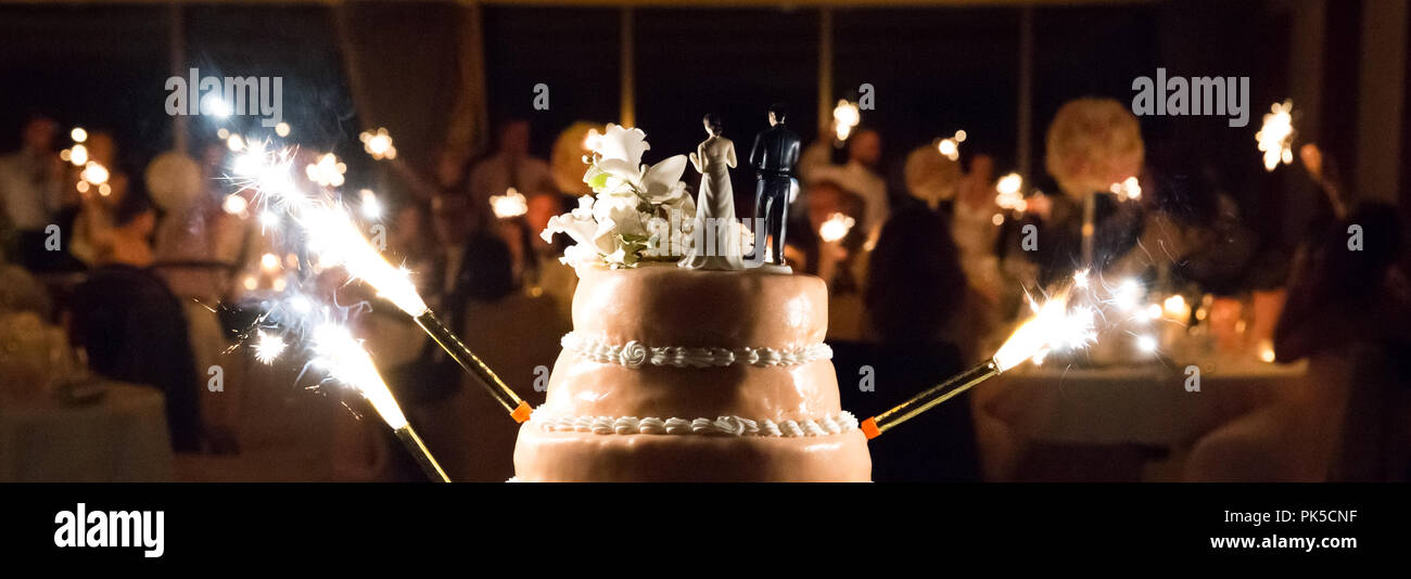 Gâteau de mariage avec des cierges et l'arrière-plan flou Banque D'Images