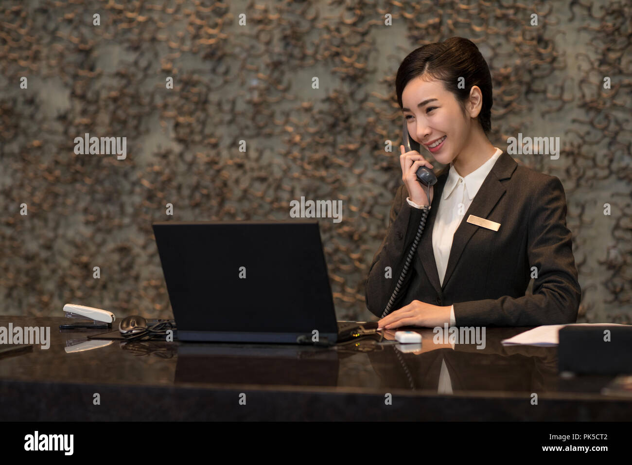 Cheerful hotel receptionist talking on the phone Banque D'Images
