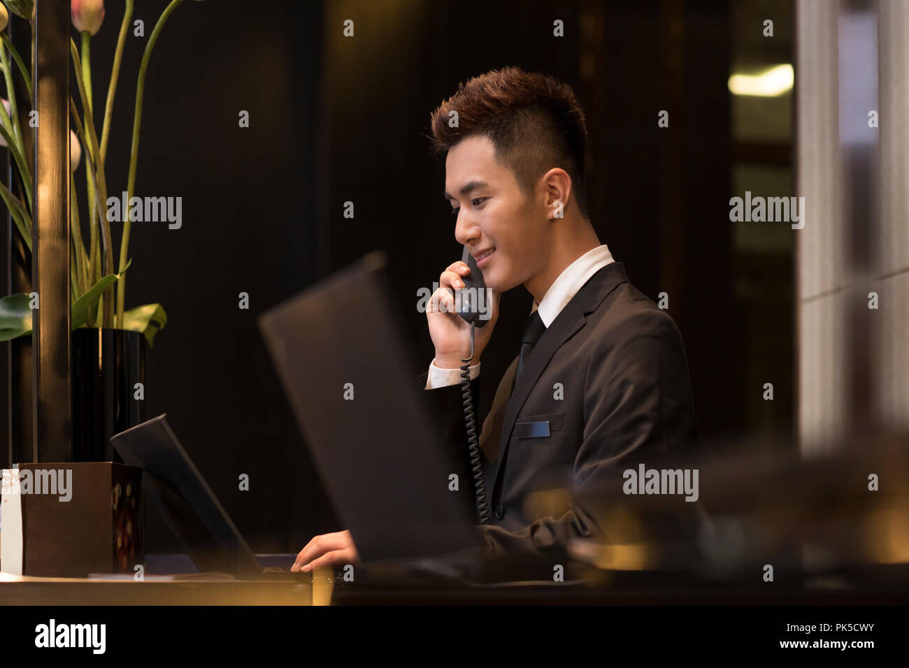 Cheerful hotel receptionist talking on the phone Banque D'Images