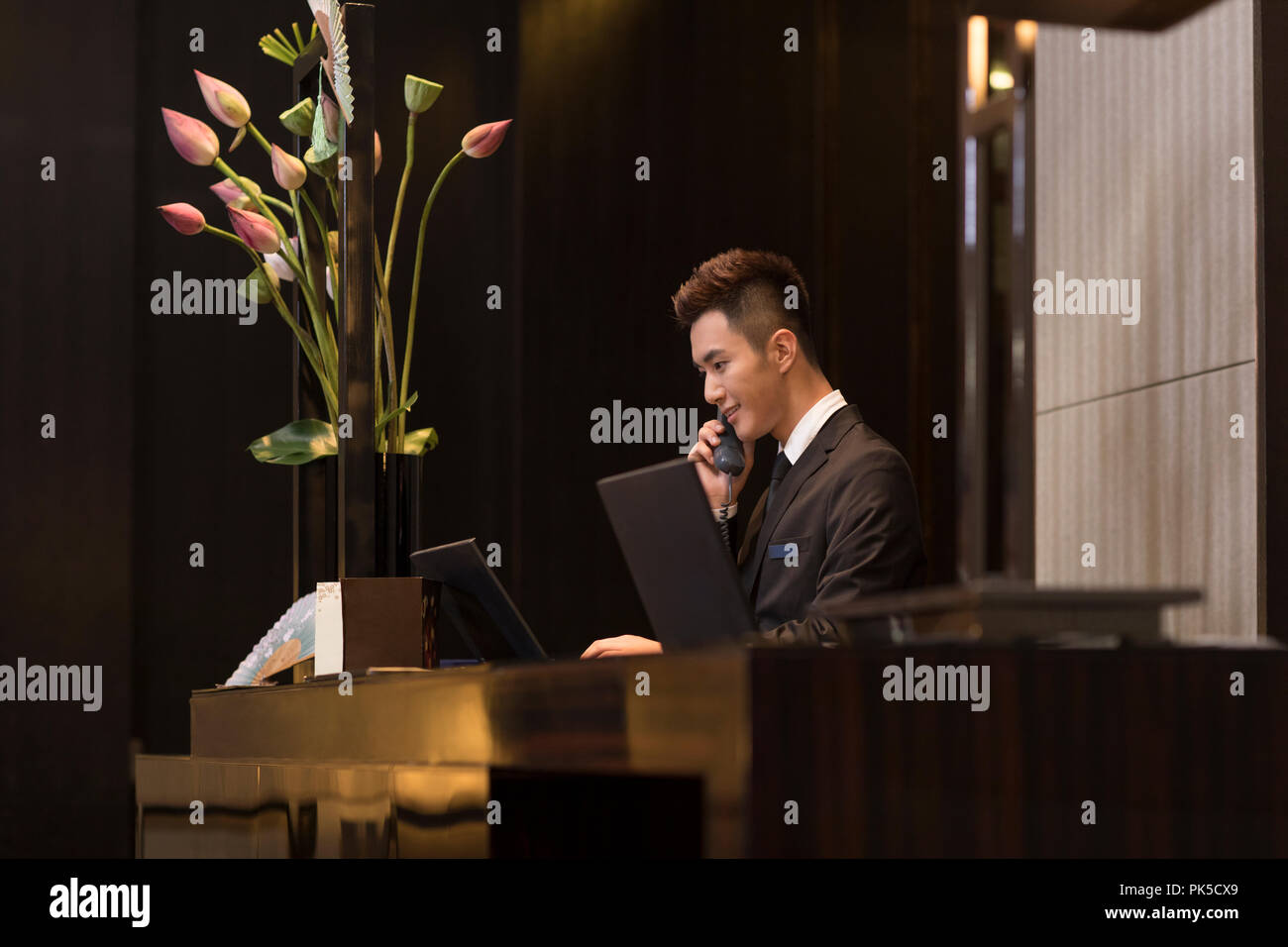 Cheerful hotel receptionist talking on the phone Banque D'Images