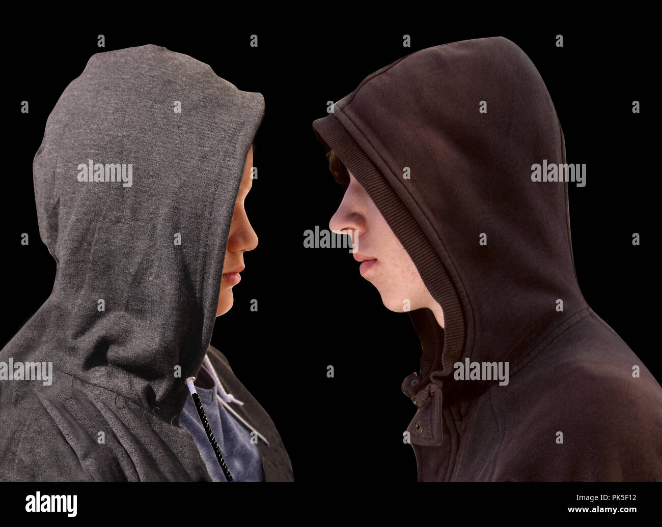 Deux adolescents en difficulté avec capuche noir debout en face de l'autre en profil isolé sur fond noir Banque D'Images