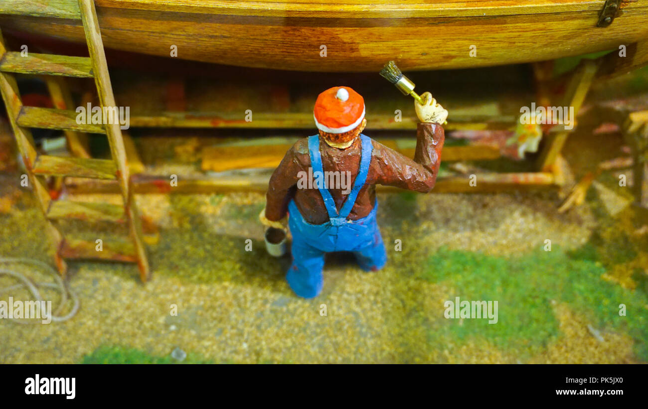 Mini figure miniature peinture travailleur un bateau au quai diorama Banque D'Images