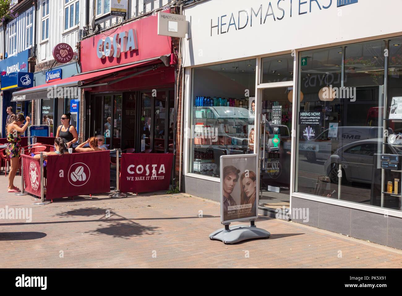 Un groupe de femmes chat à l'extérieur d'un café Costa sur Orpington High Street, dans le soleil de l'été. Juste à côté, est un salon de coiffure, London Borough of Bromley, Royaume-Uni Banque D'Images