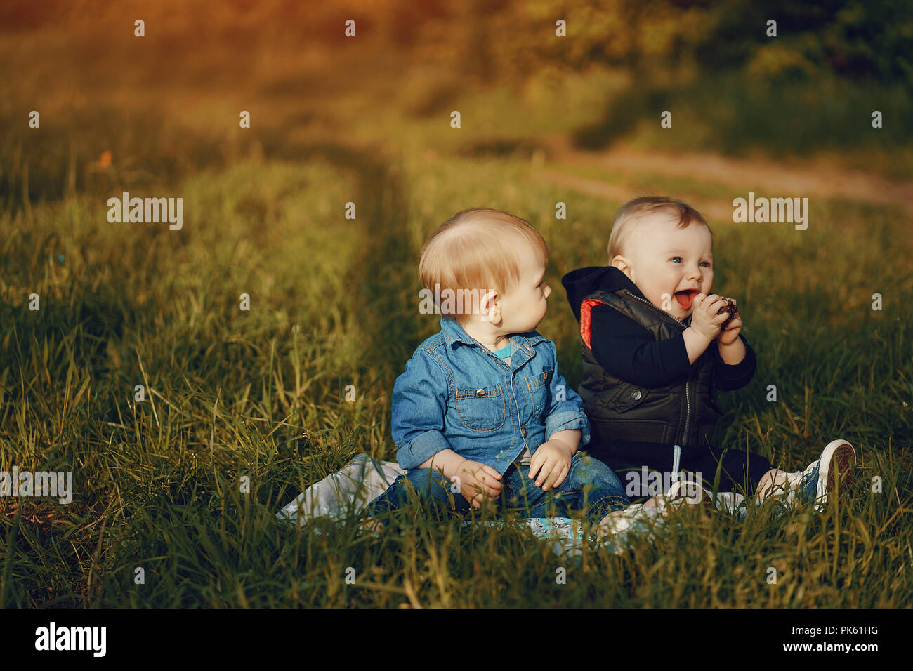 Deux jeunes garçons assis sur l'herbe dans le parc solaire d'été Banque D'Images