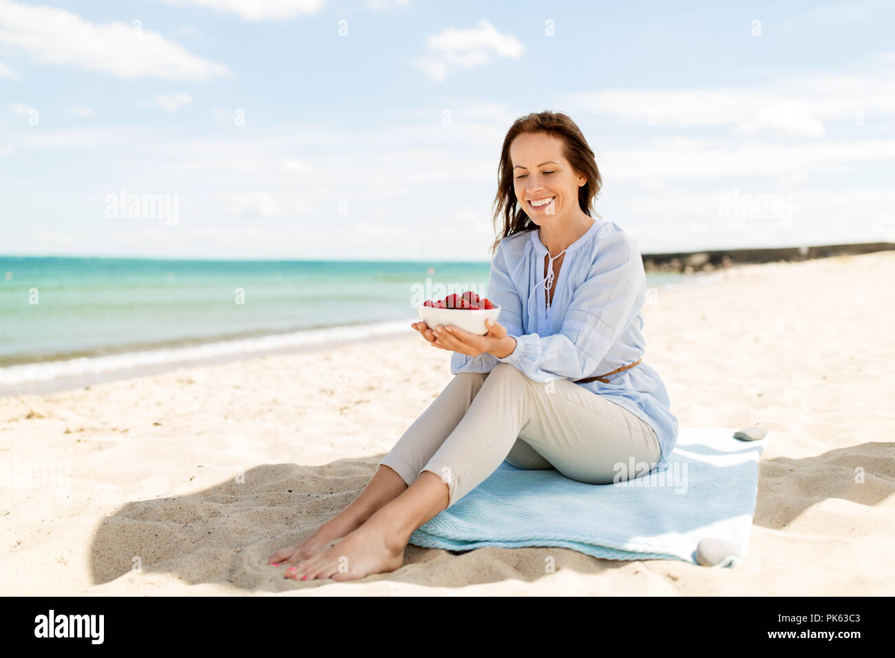 Femme heureuse avec des fraises sur plage d'été Banque D'Images