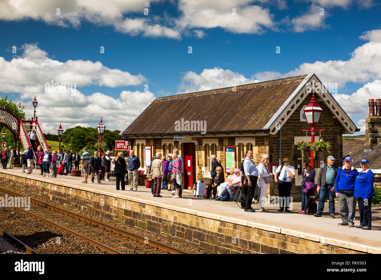UK, Yorkshire, régler,passagers sur la plate-forme de la gare en attente de s'installer à Carlisle Railway Line train dans sunshine Banque D'Images