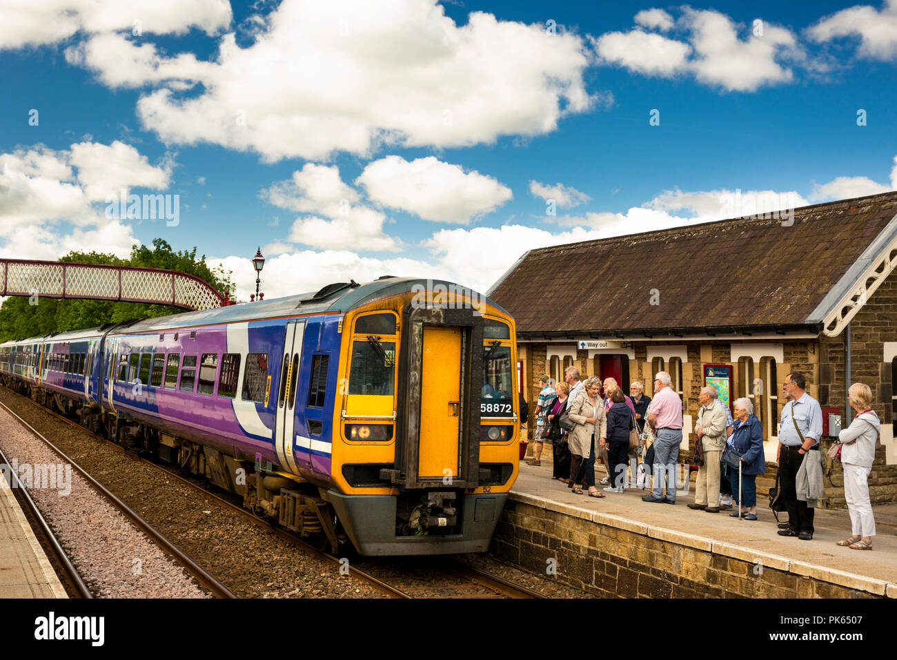 UK, Yorkshire, régler, les passagers sur la plateforme de la gare de chemin de fer en attente de s'installer à Carlisle Railway Line train dans sunshine Banque D'Images