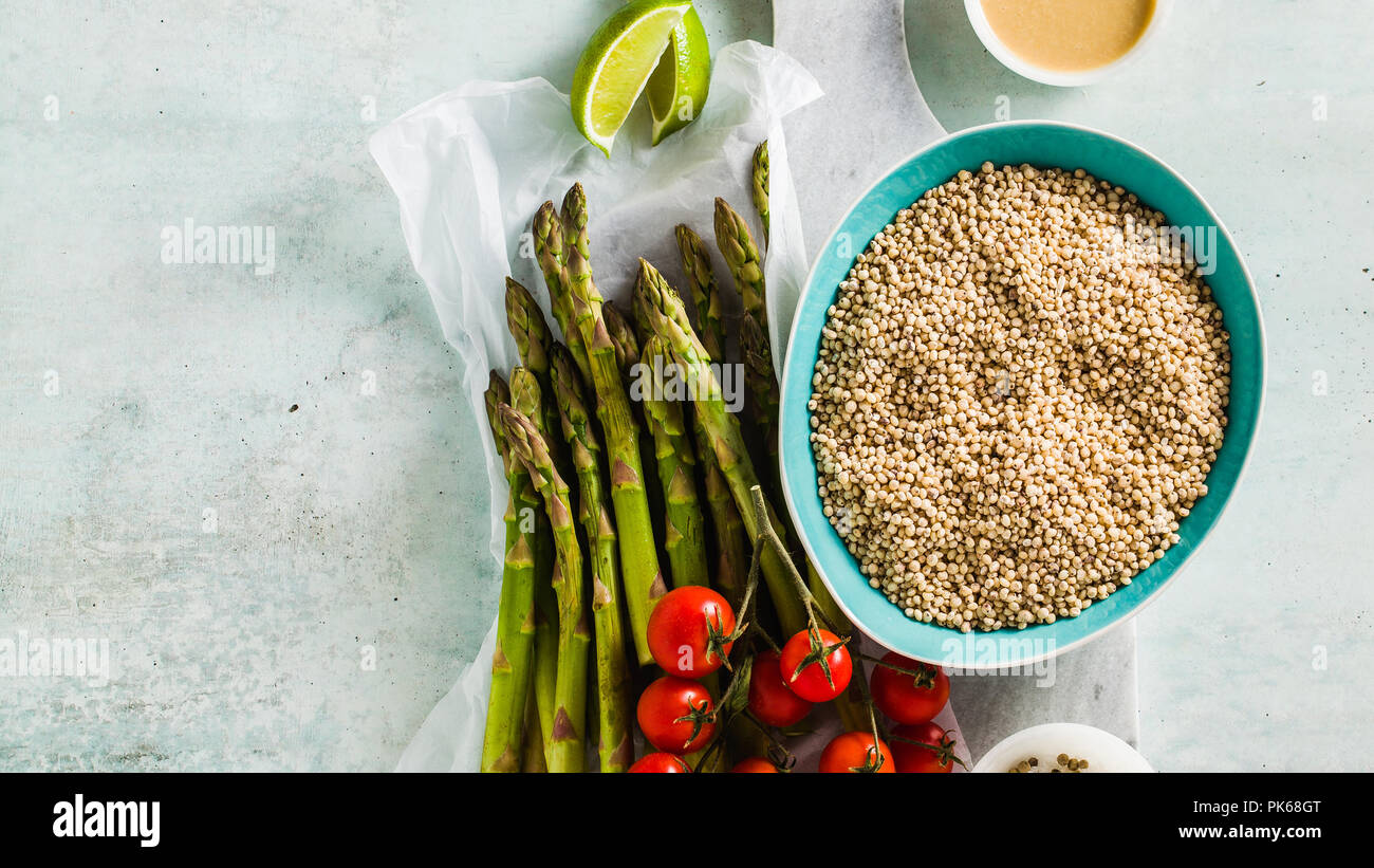 Bannière de sorgho ou grand milet aux asperges vertes et tomates cerises sur la table. Ingrédients pour des recettes sans gluten pour une cuisine saine. Banque D'Images