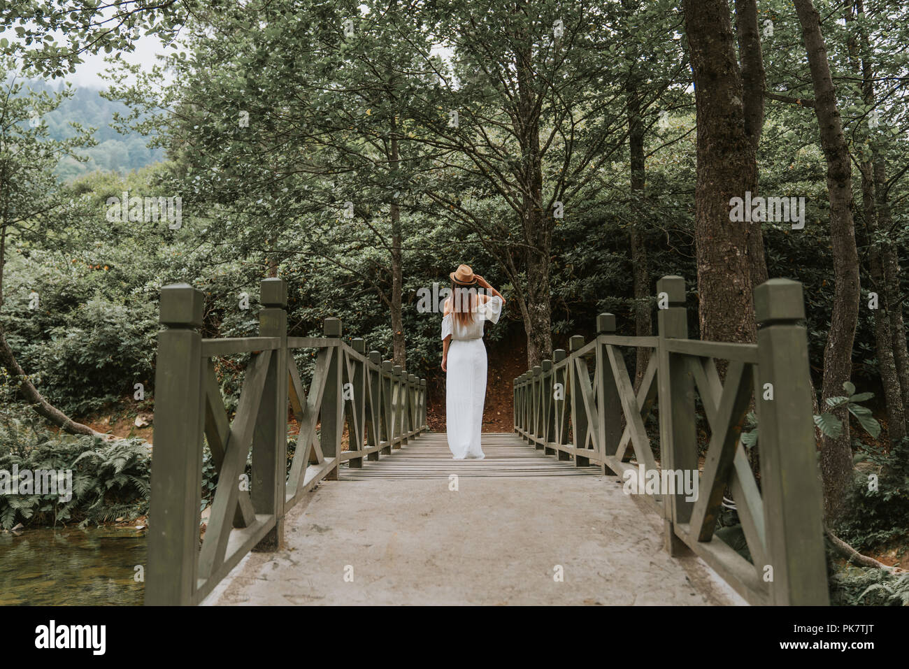 La femme avec chapeau et robe blanche debout sur pont de bois dans la nature. Banque D'Images