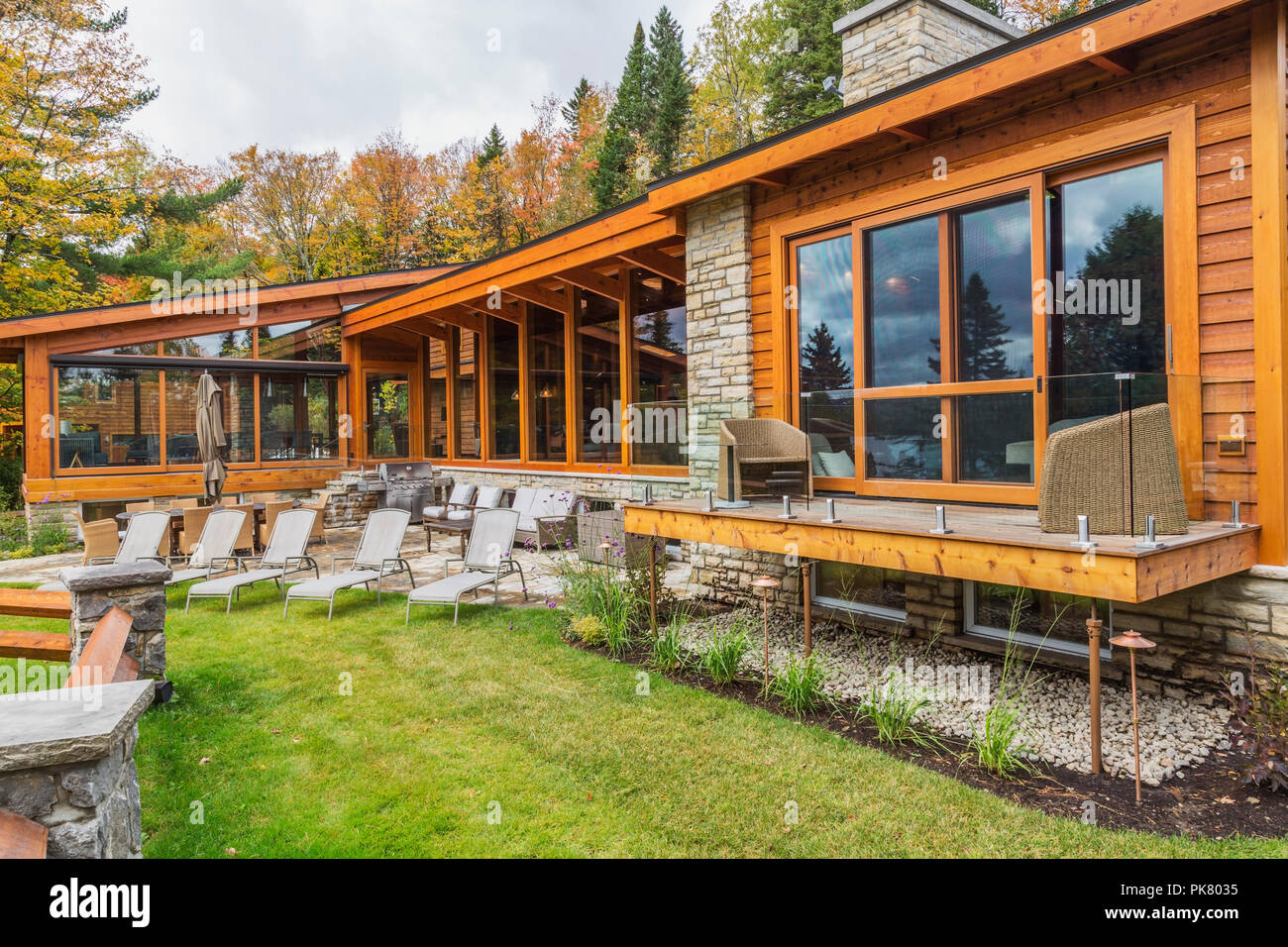 Vue arrière du cèdre et du bois teinté de luxe maison en bois avec des fenêtres panoramiques, terrasse et patio en pierre naturelle en automne, Québec Banque D'Images