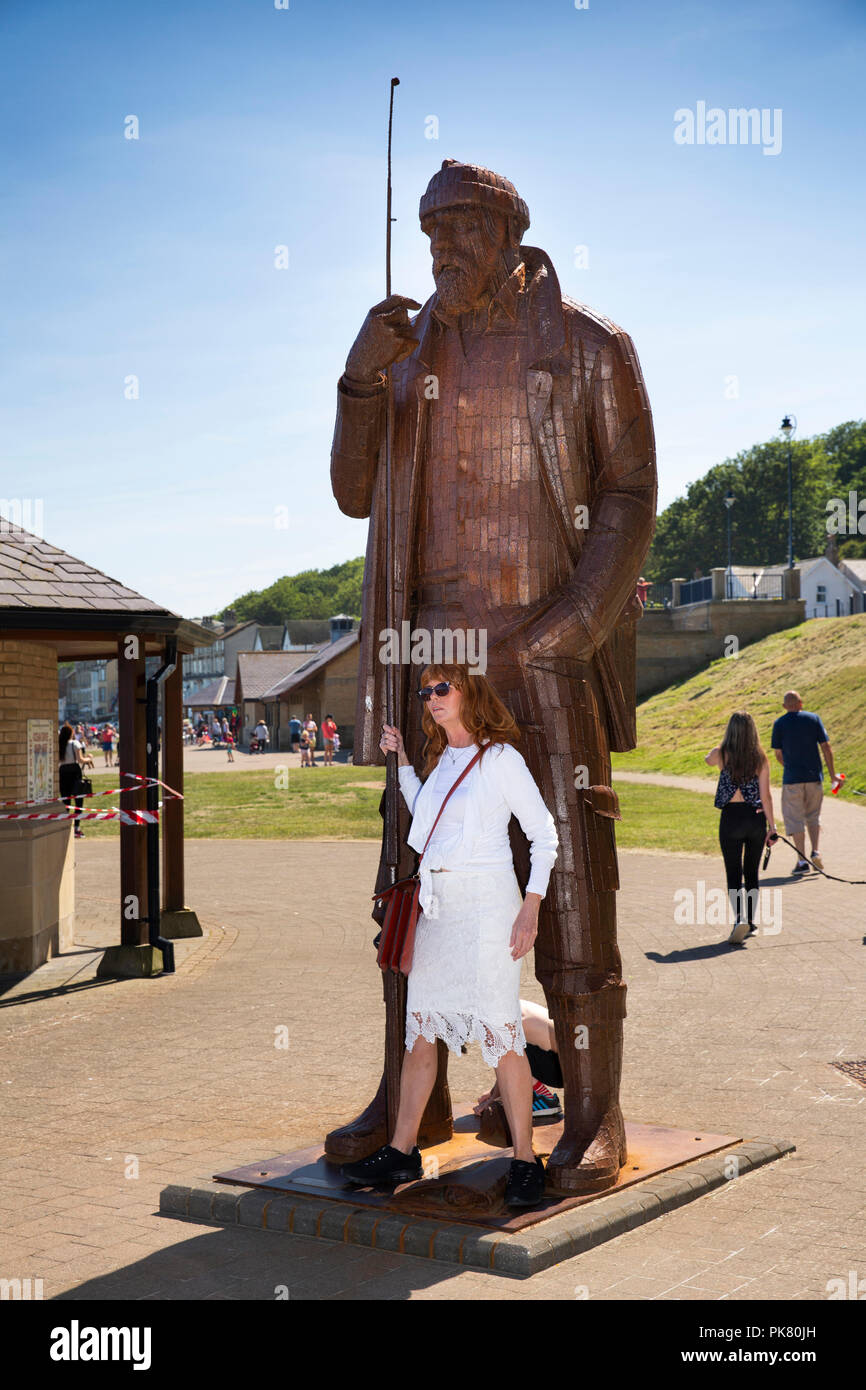 Royaume-uni, Angleterre, dans le Yorkshire, Filey, promenade, une marée haute en bref wellies pêcheur acier sculpture par Ray Lonsdale, woman posing for souvenir photograp Banque D'Images