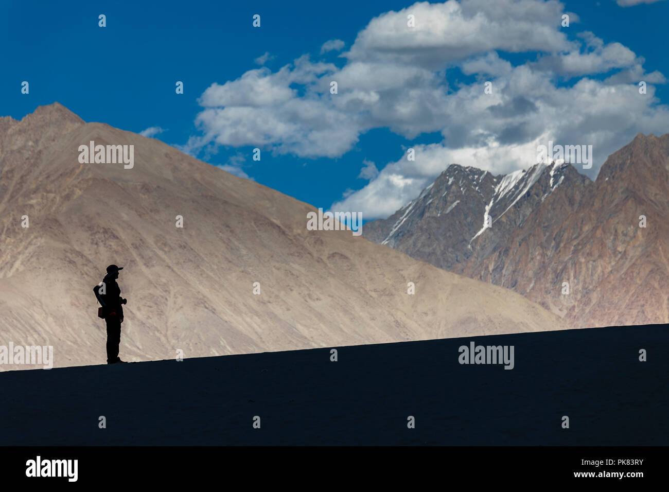 Silhouette d'un photographe sur la toile de fond de montagnes dans les dunes de sable de la vallée de Nubra au Ladakh, Inde Banque D'Images