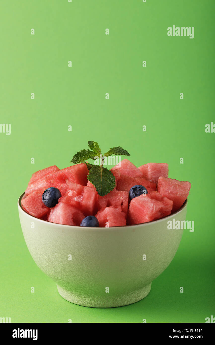 ​​Slices en tranches de melon avec des bleuets dans une assiette sur un fond vert. La nourriture avec un espace réservé au texte Banque D'Images