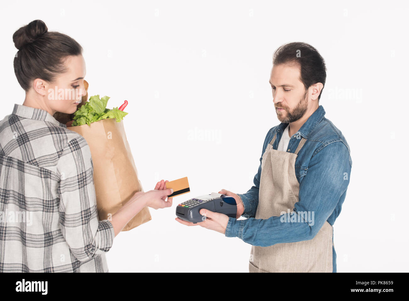 Vue de côté de femme avec emballage du papier avec de la nourriture en donnant une carte de crédit pour shop assistant avec lecteur de carte-clé isolated on white Banque D'Images