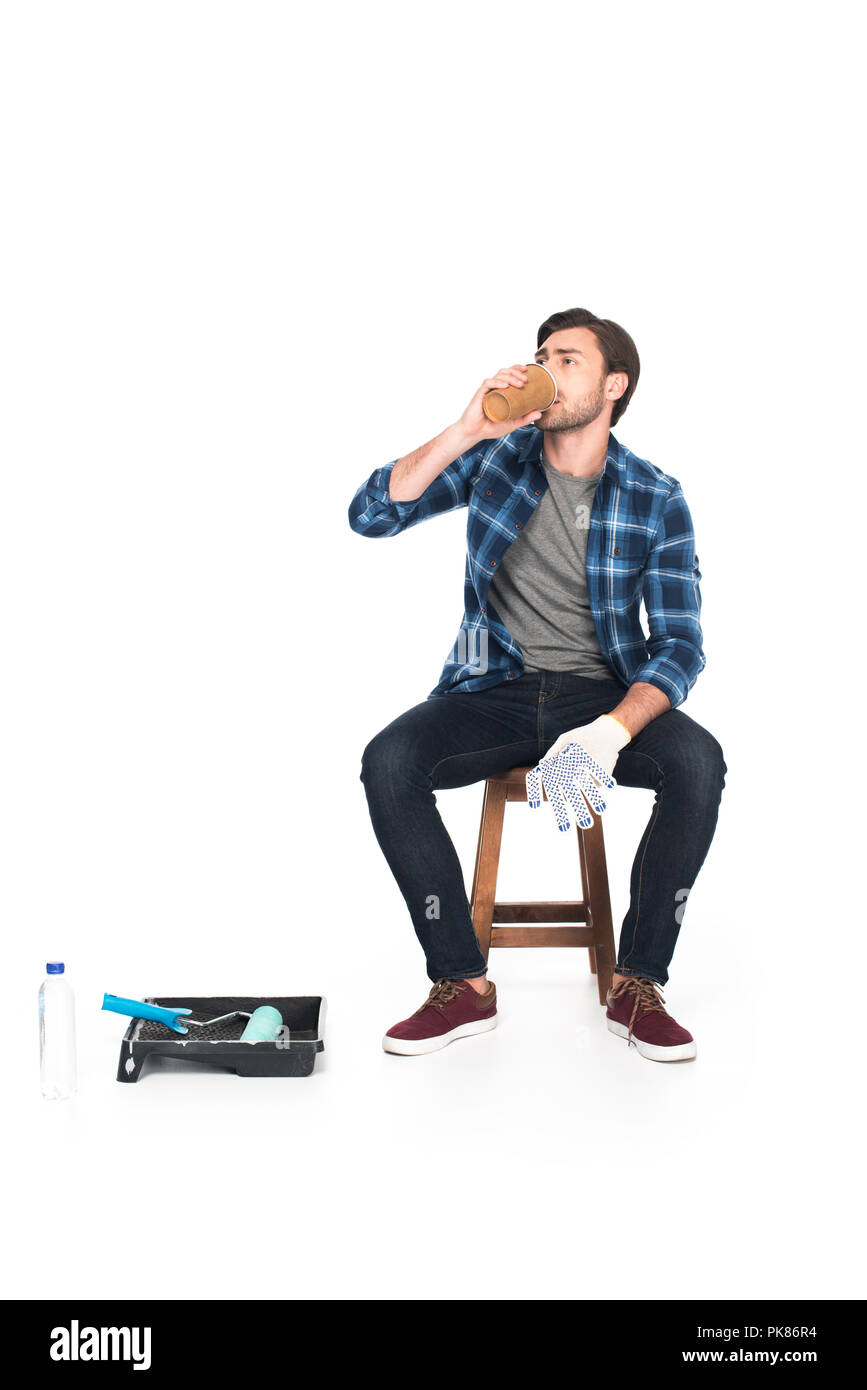 Man resting on chair et boire du café près de plateau à rouleaux rouleau à peinture et isolé sur fond blanc Banque D'Images