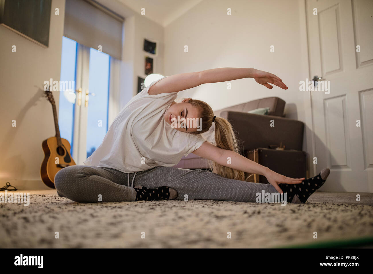 L'université est en train de faire du yoga dans son salon. Banque D'Images