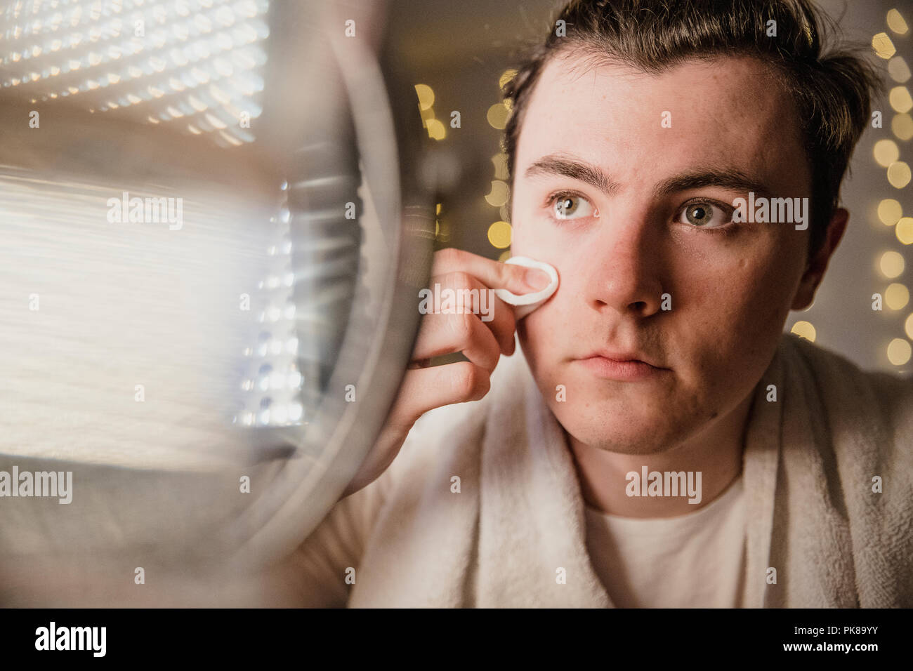 Jeune homme est son visage tonifiant au cours de sa routine de soins à domicile. Banque D'Images
