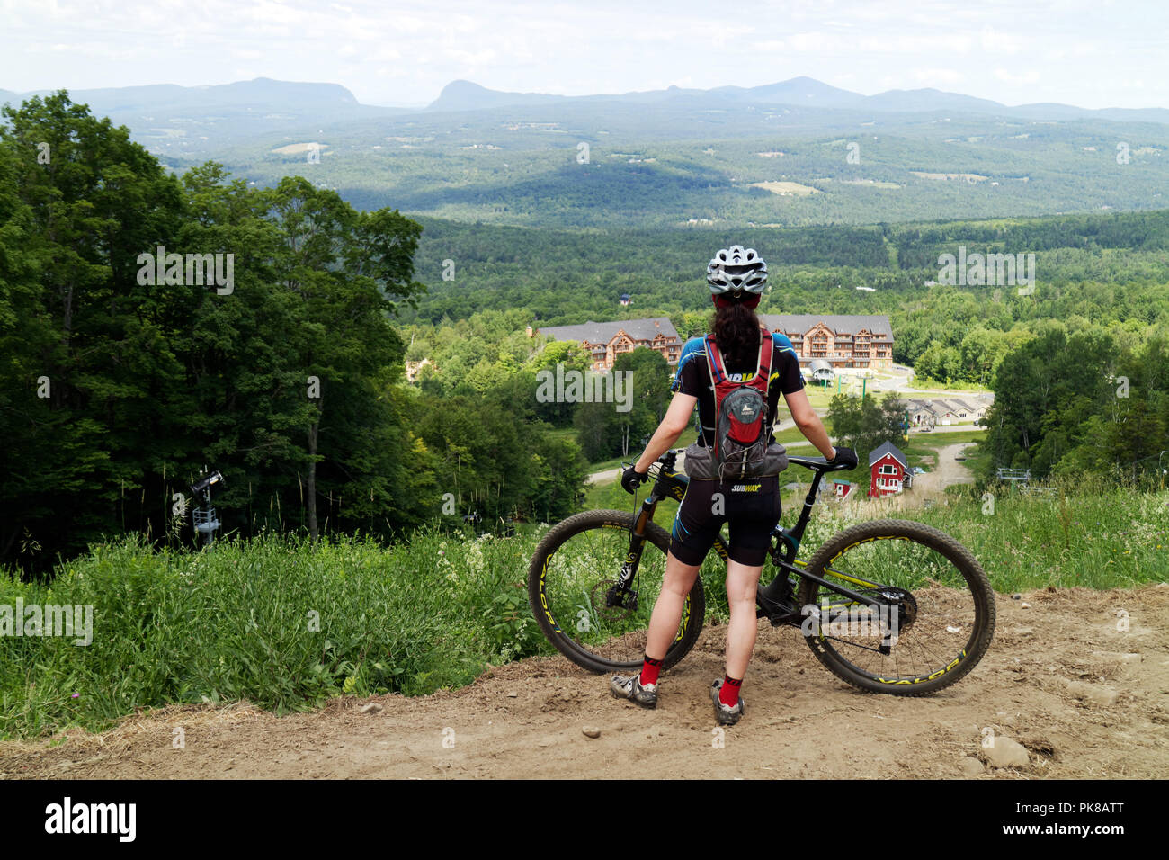 Une dame du vélo de montagne (dans son 40s) marque une pause pour admirer la vue sur le parc de vélo de montagne des sentiers du Royaume dans l'Est de Burke, Vermont, Etats-Unis Banque D'Images